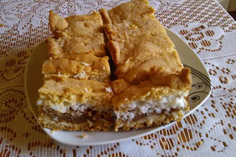 Pyszne ciasto z jabłkami i kokosem, pokrojone na kawałki, leży na talerzu.