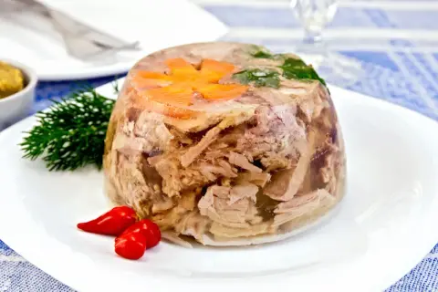 Pyszna galareta wieprzowa z marchewką i koperkiem, podana z papryczkami chili. Czas jej tężeje to kwestia cierpliwości.