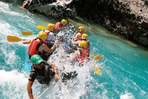 Un gruppo si diverte con il rafting nelle Marche, pagaiando tra spruzzi d'acqua cristallina e rocce imponenti. Un'avventura emozionante!
