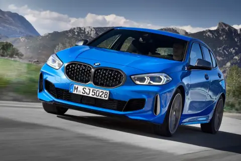 Niebieskie BMW Serii 1 F40 pędzi po górskiej drodze, kierowca skupiony na trasie.
