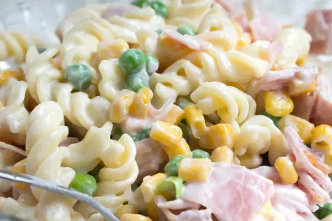Ein einfacher Nudelsalat mit Spiralnudeln, Erbsen, Mais und Schinken in cremiger Soße.