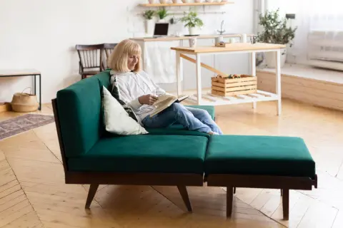 Mujer lee en un sofá modular verde, un ejemplo de muebles que se transforman para adaptarse a tu espacio y estilo de vida.