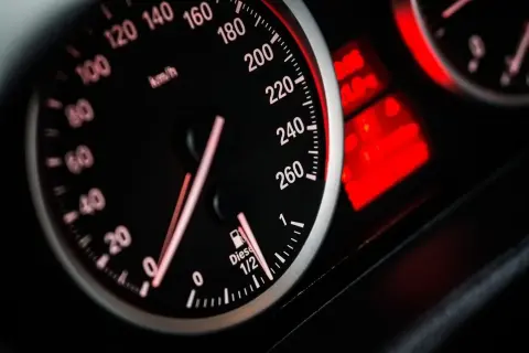Zbliżenie na deskę rozdzielczą samochodu. Prędkościomierz pokazuje ok. 60 km/h. Wskaźnik paliwa jest na 1/2. Dowiedz się, jak obliczyć spalanie paliwa na 100 km.