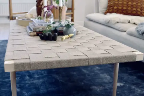 Ett unikt diy soffbord med flätad topp och träben. Prydnader som en guldfärgad myra och en liten vas ger liv åt bordet.