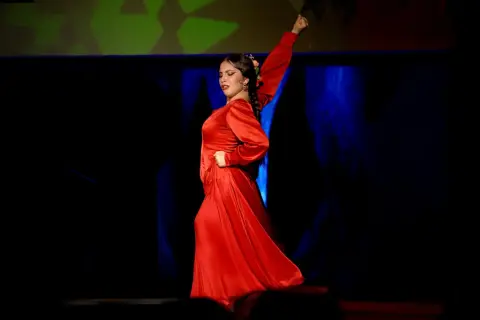 Una bailaora de flamenco, vestida de rojo pasión, evoca la fuerza y elegancia de los grupos de sevillanas.