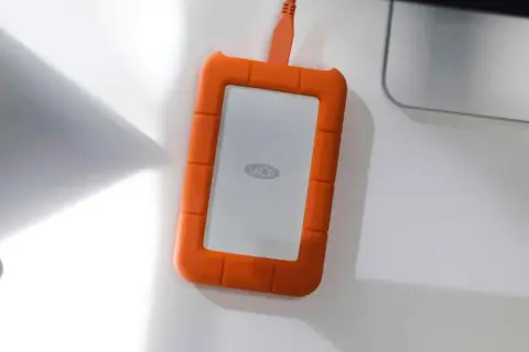 Pomarańczowy dysk LaCie z logo, podłączony kablem. Idealny do backupu danych w trybie raid 1.