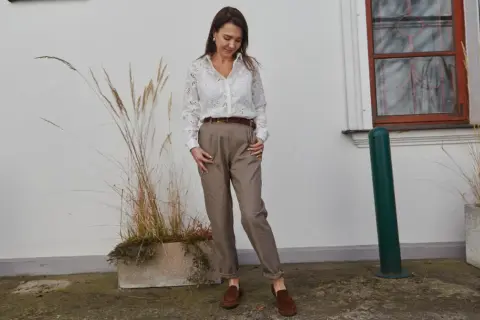 Elegancka stylizacja do pracy: biała koszula z haftem, brązowe spodnie i mokasyny. Inspiracja, jak się ubrać do pracy.