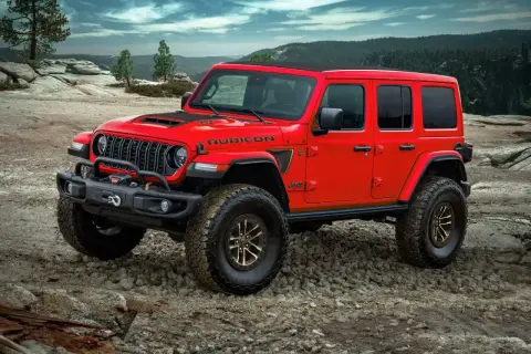 Czerwony Jeep Rubicon na kamienistym podłożu, gotowy na przygodę. Nawet przy wysokich **kosztach paliwa**, ten terenowy potwór oferuje niezapomniane wrażenia.