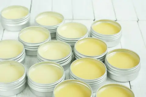Piccoli barattoli argentati pieni di balsamo giallo, un prodotto naturale a base di cera d'api, pronti per essere usati.