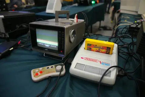 Stary monitor JVC, konsola Pegasus IQ-502 z żółtą kasetą i kontroler Micro Genius.