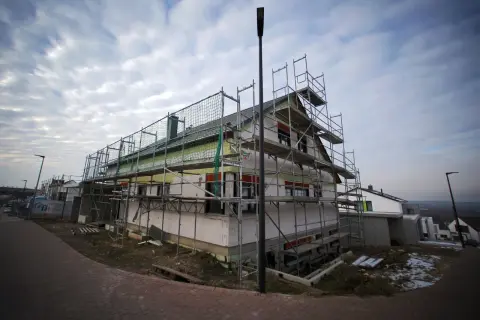 Haus im Bau mit Gerüst und Dämmung unter bewölktem Himmel.