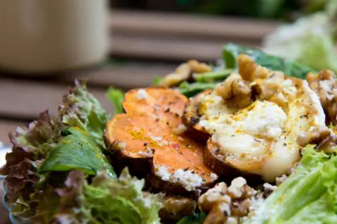 Ensalada de boniato asado con queso de cabra, nueces y hojas verdes.