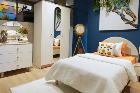 Ein gemütliches boho style jugendzimmer mit weißem Bett, Kleiderschrank und Kommode. Ein buntes Chamäleon-Bild ziert die Wand.
