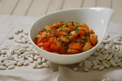 Schmackhafte weiße Bohnen in Tomatensoße, garniert mit Schnittlauch. Die Frage "wie lange bohnen kochen" wird hier visuell beantwortet.