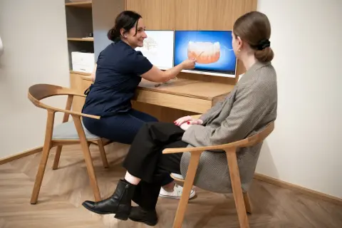 Dentystka pokazuje pacjentce na ekranie, jak prawidłowo dbać o higienizację zębów.