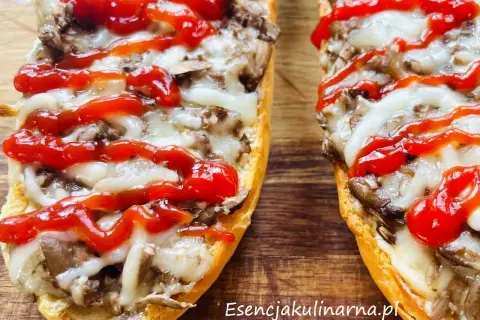 Zapiekanki z pieczarkami i serem na chrupiącej bagietce, polane ketchupem.