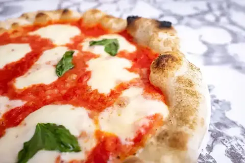 Pyszna pizza margherita z rozpływającym się serem mozzarella, sosem pomidorowym i świeżą bazylią na chrupiącym cieście.