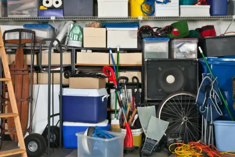 Organizzazione garage con idee cantina fai da te: scatole, attrezzi, slitta, ruote, casse audio e contenitori blu.
