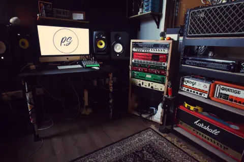Wygodne domowe studio z monitorem, sprzętem audio i gitarami. Idealne miejsce do tworzenia muzyki.