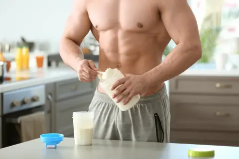 Muskulöser Mann bereitet Proteinshake zu. Informiere dich über mögliche proteinpulver nebenwirkungen, bevor du es verwendest.