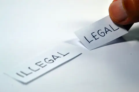 Kciuk przesuwa kartkę z napisem "LEGAL", obok leży kartka z napisem "ILLEGAL". Czy to było niedawno, czy nie dawno?