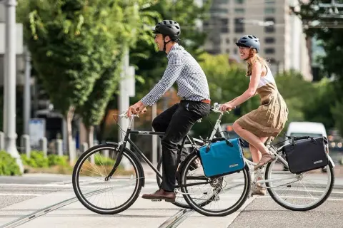 Ein Paar radelt mit Gepäcktaschen durch die Stadt. Perfekt für eine ADFC Fahrradtour, die Liste der Ausrüstung ist komplett.