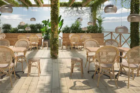 Terrasse mit Rattanmöbeln und Blick aufs Meer.