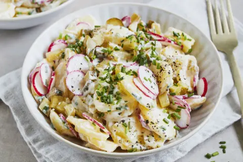 Kartoffelsalat mit Joghurt, Radieschen und Schnittlauch, garniert mit Pfeffer. Ein leichter und frischer Genuss.