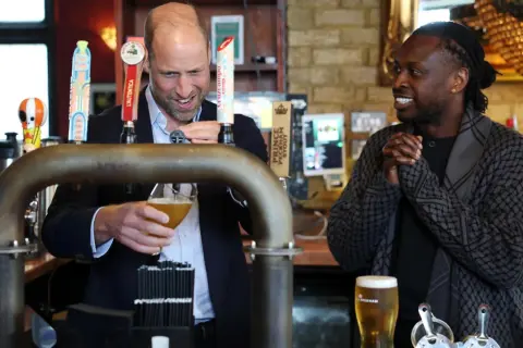 Uomo che versa una pinta di birra, mentre un altro uomo sorride.