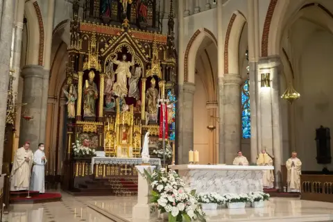 W kościele trwa msza. 1 maja święto kościelne, kapłani w szatach liturgicznych przy ołtarzu.