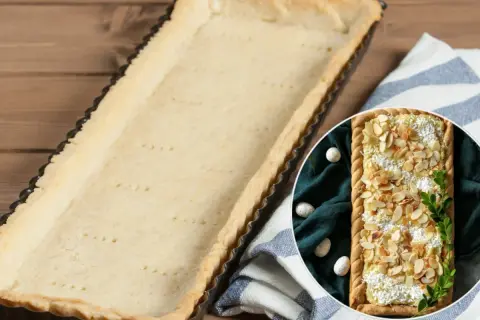Pusta, upieczona masa do mazurka w formie czeka na nadzienie. Obok w okręgu widać gotowy mazurek z migdałami.