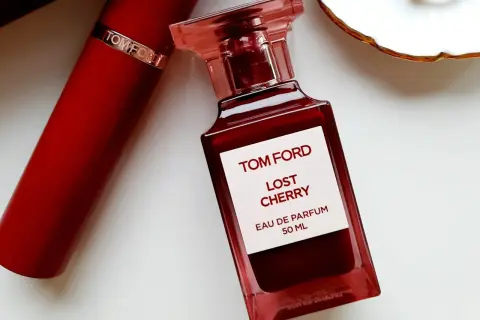 Elegancka butelka perfum Tom Ford Lost Cherry 50 ml w odcieniu głębokiej czerwieni, obok czerwonego opakowania.