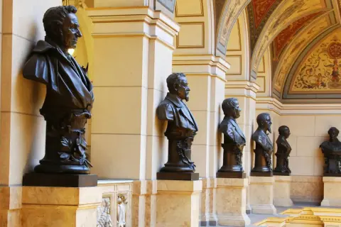 Büsten von Männern im Nationalmuseum Prag, flankiert von Säulen und einer reich verzierten Decke.