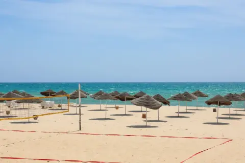 Piękna plaża w Tunezji we wrześniu. Słoneczna pogoda, turkusowe morze i rzędy parasoli zapraszają do relaksu.