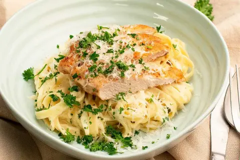 En krämig pasta alfredo kyckling, toppad med färsk persilja och riven parmesan. En utsökt måltid!