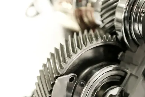 Metalowe koła zębate, część skomplikowanej przekładni ciernej, lśnią w zbliżeniu.