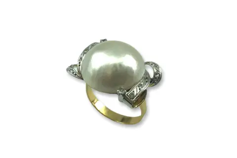 Anillo de oro con un gran anillo perla japonesa central, rodeado de pequeños diamantes incrustados en filigrana de plata.