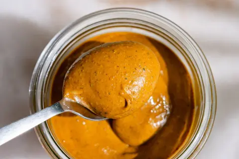 Une cuillère déborde de beurre de pistache onctueux, prêt à être dégusté. Une recette maison facile à réaliser.