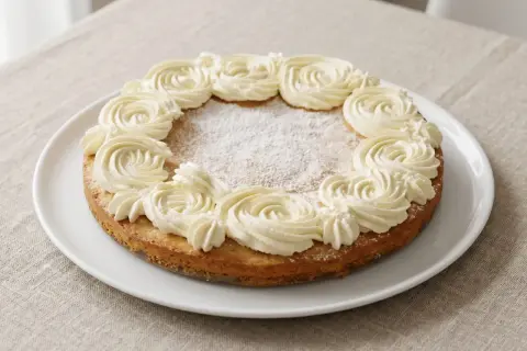 En härlig semmelkladdkaka glutenfri med fluffig grädde runt kanten, pudrad med florsocker.