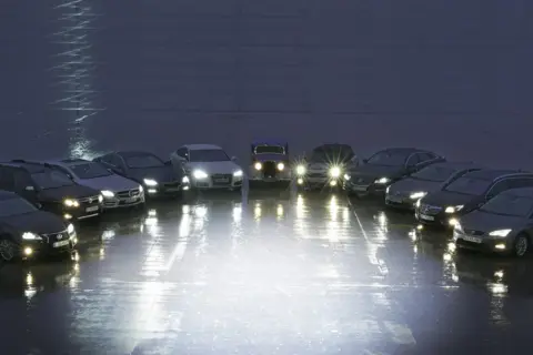 Różne rodzaje lamp samochodowych prezentowane na tle nocnego nieba. Od klasycznych reflektorów po nowoczesne LED-y, każdy pojazd oświetla drogę na swój sposób.