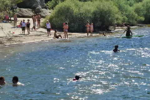 Gente disfrutando en la playa y el agua. Para llegar a esta playa, pita el camino.