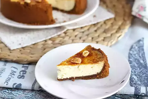 Tranche de cheesecake ricotta onctueux, garnie de noisettes caramélisées. Un délice gourmand.