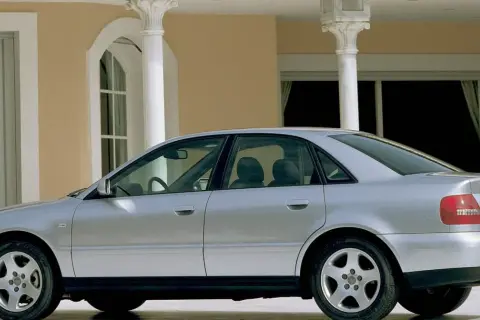 Srebrne Audi A4 B5, sedan, stoi przed budynkiem z kolumnami.