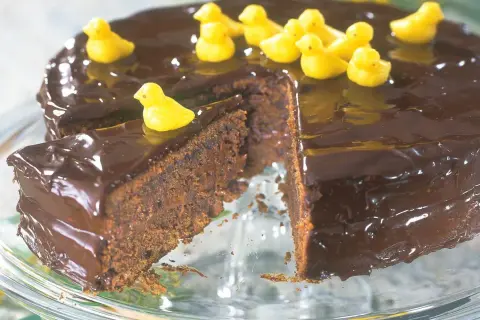 En saftig chokladtårta med blank glasyr, dekorerad med små gula kycklingar. En perfekt påsktårta för alla chokladälskare!