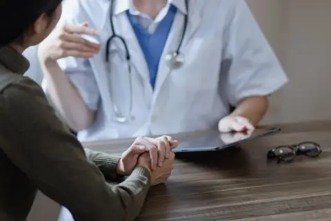 Pacjentka rozmawia z lekarzem, który korzysta z tabletu. Czy lekarz POZ widzi prywatne wizyty?