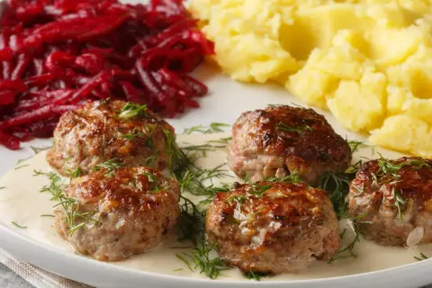 Soczyste klopsy w sosie z koperkiem, podane z purée ziemniaczanym i buraczkami.