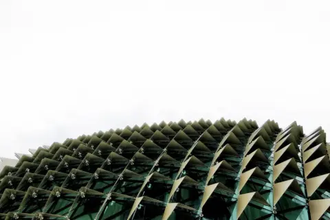 Edificio con facciata a squame triangolari, che ricorda i materiali a cambiamento di fase per la sua struttura dinamica e adattiva.