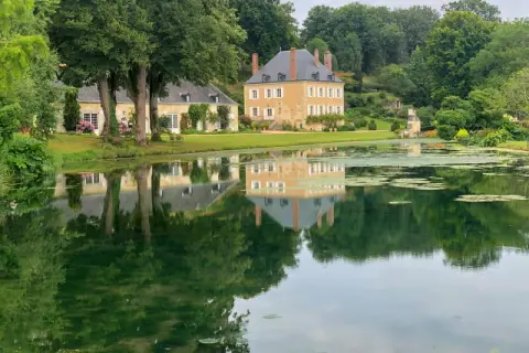 Le jardin du Plessis Sasnières, avec son étang paisible reflétant le château et ses arbres majestueux, offre une vue d'une beauté intemporelle.