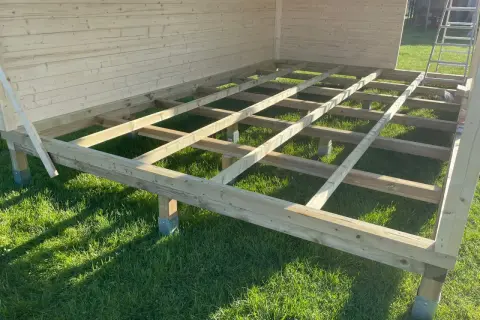 Holzkonstruktion für das **fundament gartenhaus** auf grünem Rasen, bereit für den Aufbau.