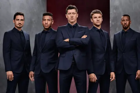 Pięciu mężczyzn w granatowych garniturach, prezentujących elegancję marki Hugo Boss.